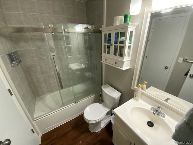 bathroom with toilet, enclosed tub / shower combo, wood finished floors, and vanity