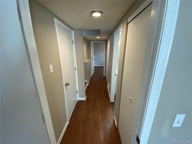 hall featuring dark wood-style floors, baseboards, and a textured ceiling
