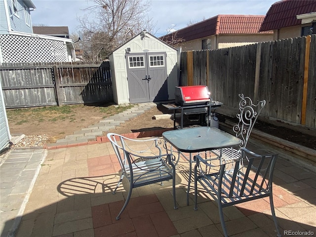 view of patio featuring an outbuilding, a fenced backyard, a storage shed, and area for grilling
