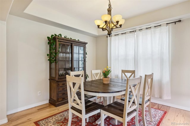 dining room with a chandelier, light wood-type flooring, and baseboards