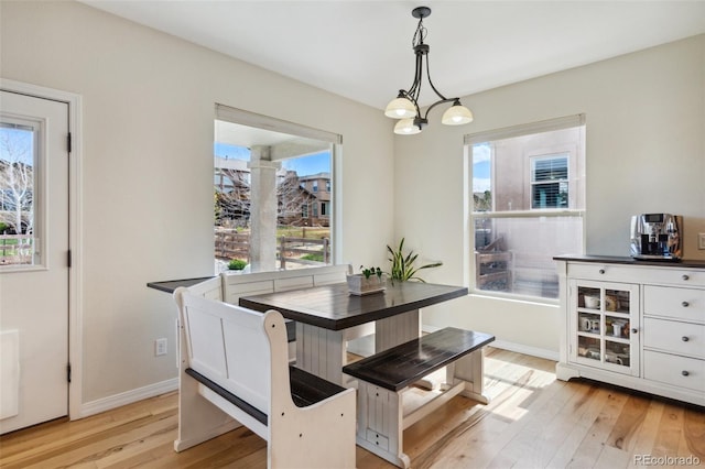 dining room featuring light wood-type flooring, baseboards, and a chandelier