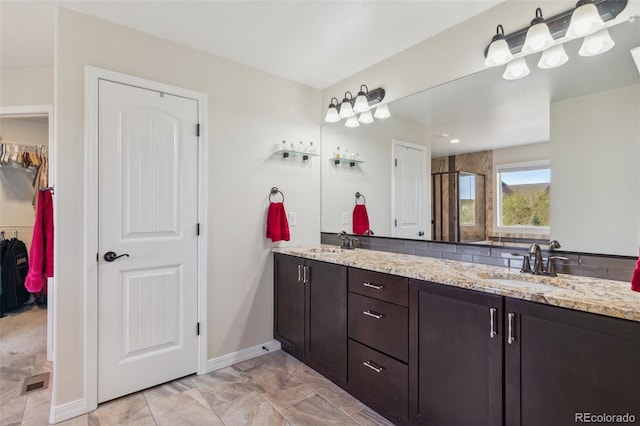 bathroom featuring double vanity, baseboards, marble finish floors, and a walk in closet