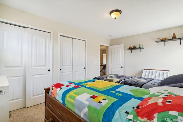 bedroom featuring two closets and light colored carpet