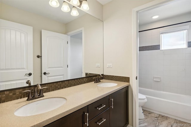 bathroom with toilet, double vanity, tub / shower combination, and a chandelier