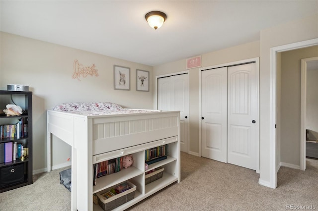 bedroom with carpet flooring, multiple closets, and baseboards