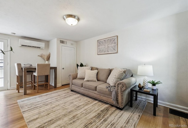 living area featuring a wall unit AC, wood finished floors, and baseboards
