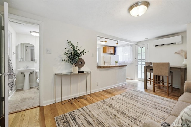 living area featuring a wall mounted AC, wood finished floors, and baseboards