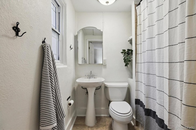 full bathroom featuring toilet, tile patterned flooring, curtained shower, and a sink