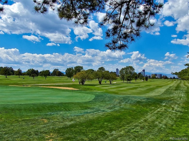 view of community featuring view of golf course, a yard, and an area to practice putting