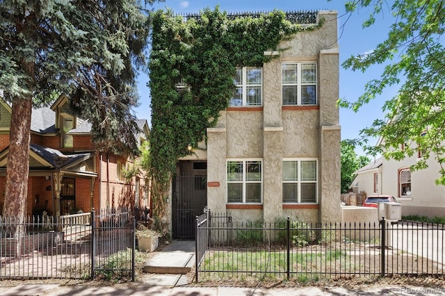 1532 N High St Unit 1, Denver, CO 80218 - view of front facade with a fenced front yard, stucco siding, and a gate