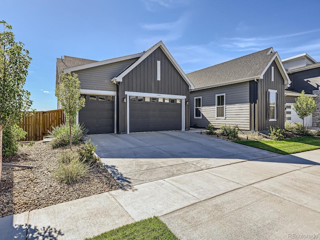 view of front of home with a garage, fence, a shingled roof, board and batten siding, and driveway
