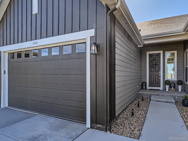 property entrance featuring a garage, board and batten siding, and driveway