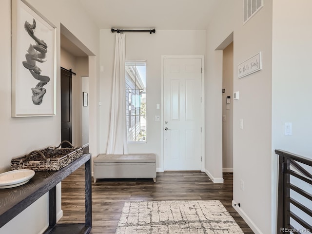 interior space featuring visible vents, a barn door, baseboards, and dark wood-style floors