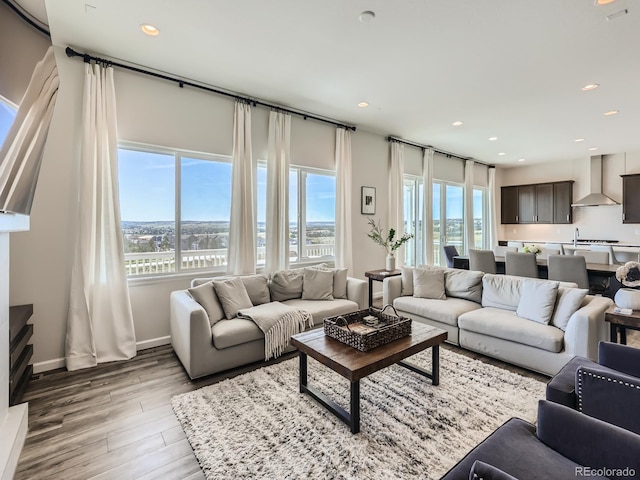 living area with recessed lighting, light wood-style flooring, a water view, and baseboards