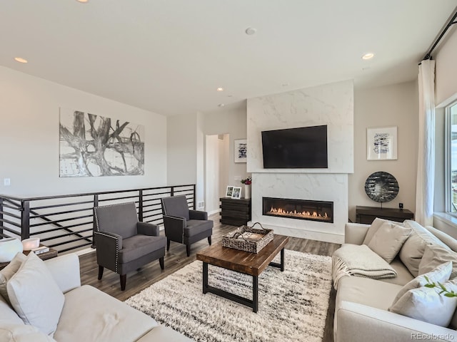 living room with recessed lighting, a high end fireplace, and wood finished floors