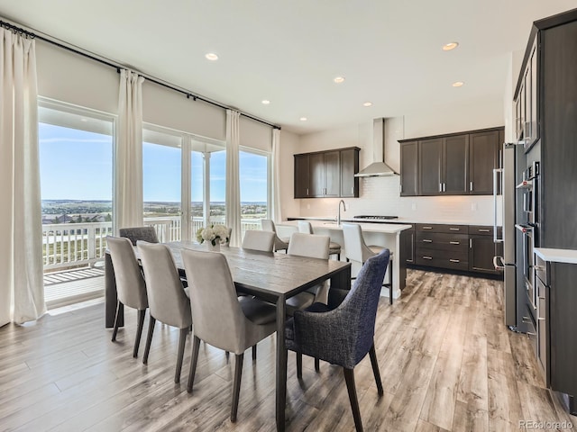dining room featuring a water view, recessed lighting, and light wood-style flooring