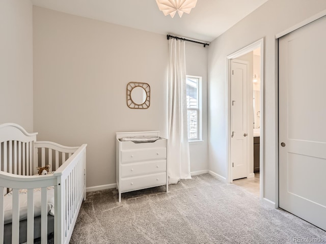 carpeted bedroom with baseboards and a crib