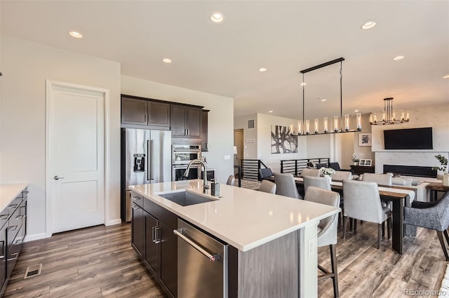14440 Hop Clover Trl, Parker, CO 80134 - kitchen with appliances with stainless steel finishes, a sink, open floor plan, wood finished floors, and light countertops