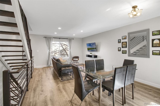 dining space with light wood finished floors, stairs, and baseboards