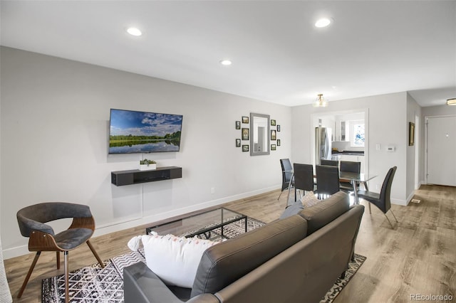 living area with baseboards, light wood-style flooring, and recessed lighting