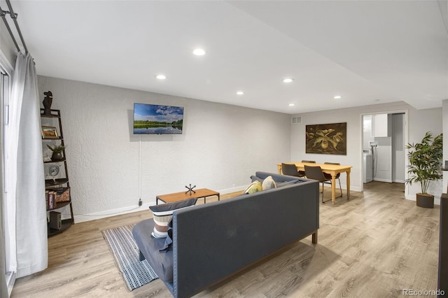 living room featuring baseboards, visible vents, light wood-style flooring, and recessed lighting