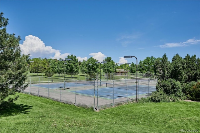 view of tennis court featuring a lawn and fence