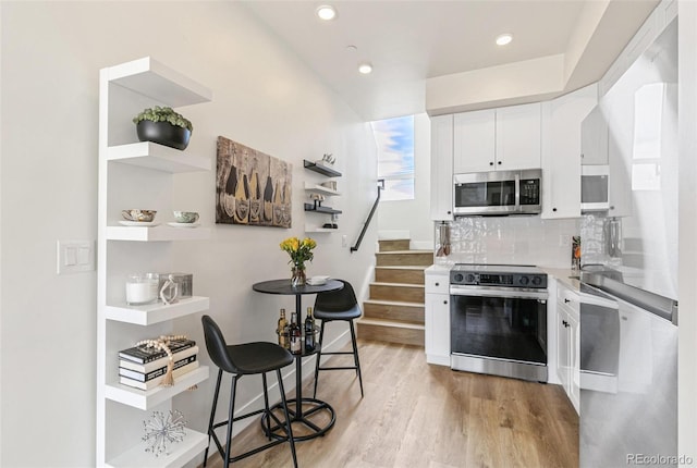 5385 W 14th Ave, Lakewood, CO 80214 - kitchen featuring appliances with stainless steel finishes, light wood-type flooring, white cabinetry, tasteful backsplash, and open shelves
