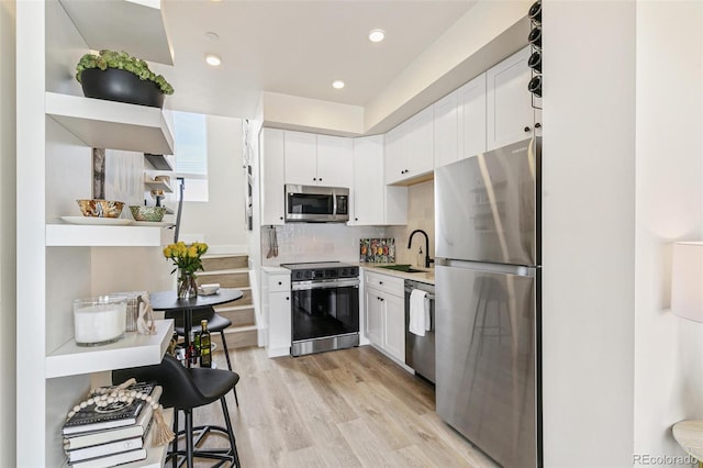 5385 W 14th Ave, Lakewood, CO 80214 - kitchen with stainless steel appliances, white cabinetry, a sink, light wood-style floors, and recessed lighting