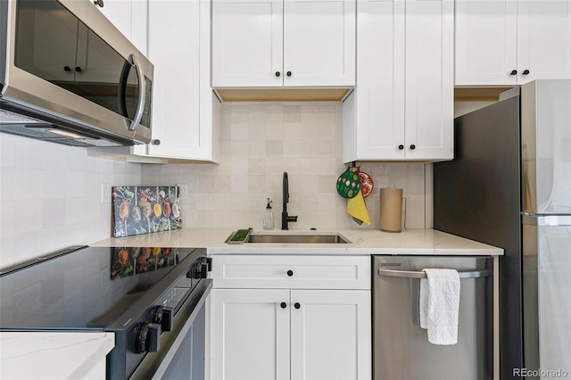 5385 W 14th Ave, Lakewood, CO 80214 - kitchen with stainless steel appliances, a sink, white cabinetry, tasteful backsplash, and light stone countertops