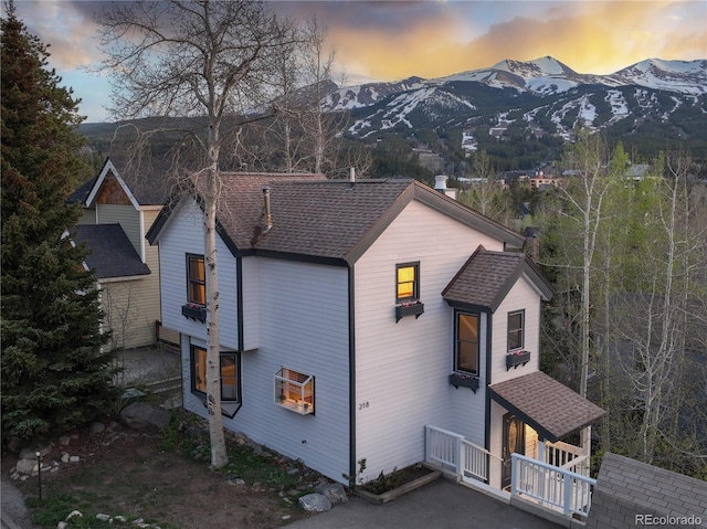 218 Highland Ter, Breckenridge, CO 80424 - property exterior at dusk featuring a mountain view, a shingled roof, and a chimney