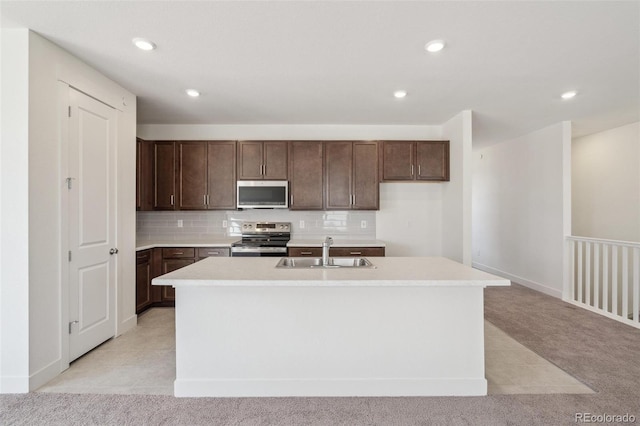 9314 Biscay St, Commerce City, CO 80022 - kitchen featuring a sink, a kitchen island with sink, light countertops, appliances with stainless steel finishes, and light carpet