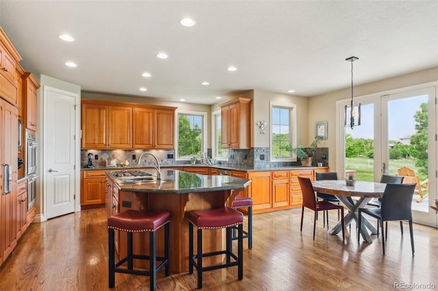 4651 Sonado Pl, Parker, CO 80134 - kitchen with light wood-style floors, tasteful backsplash, recessed lighting, a kitchen island with sink, and a breakfast bar area