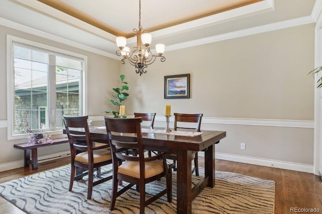 4651 Sonado Pl, Parker, CO 80134 - dining space featuring a raised ceiling, a chandelier, ornamental molding, and wood finished floors