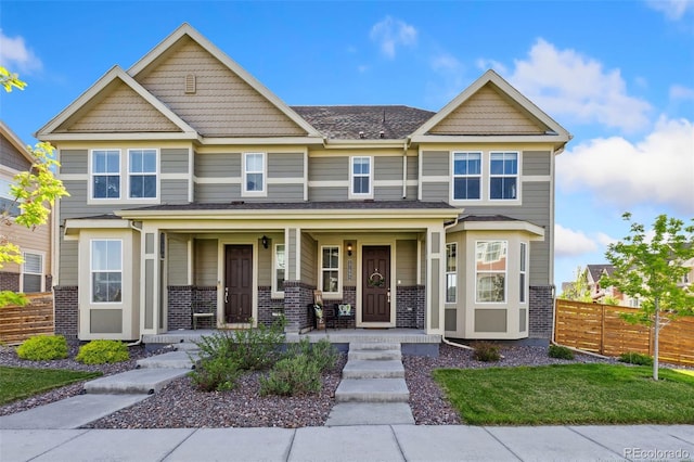 view of front of home featuring fence, brick siding, and a porch