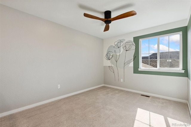 carpeted spare room featuring a ceiling fan and baseboards