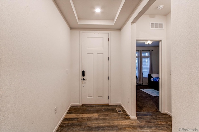 hallway with dark hardwood / wood-style floors and a tray ceiling