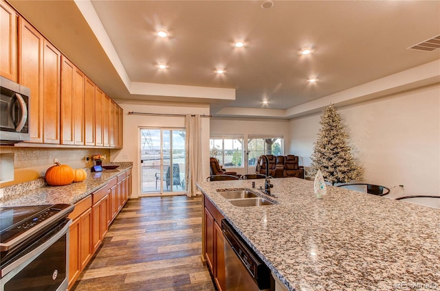 kitchen with light stone countertops, stainless steel appliances, sink, and dark hardwood / wood-style flooring