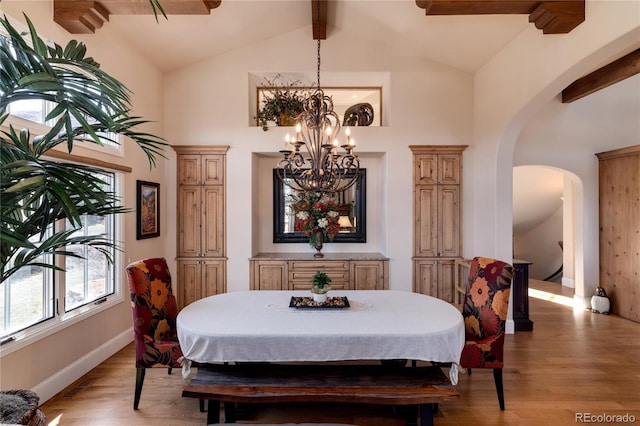 dining area with vaulted ceiling with beams, a chandelier, and light wood-type flooring