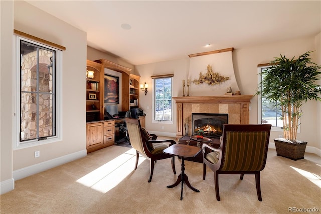 sitting room featuring a tile fireplace, light carpet, and built in desk