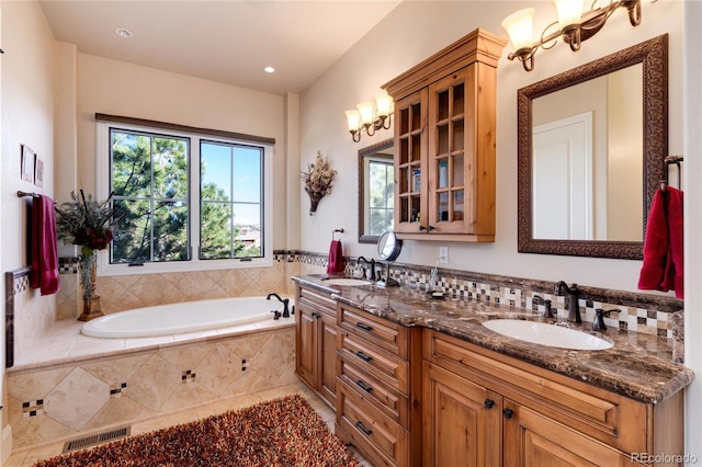 bathroom featuring a relaxing tiled tub, vanity, and an inviting chandelier