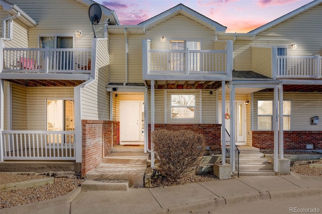 multi unit property with brick siding, entry steps, and a balcony