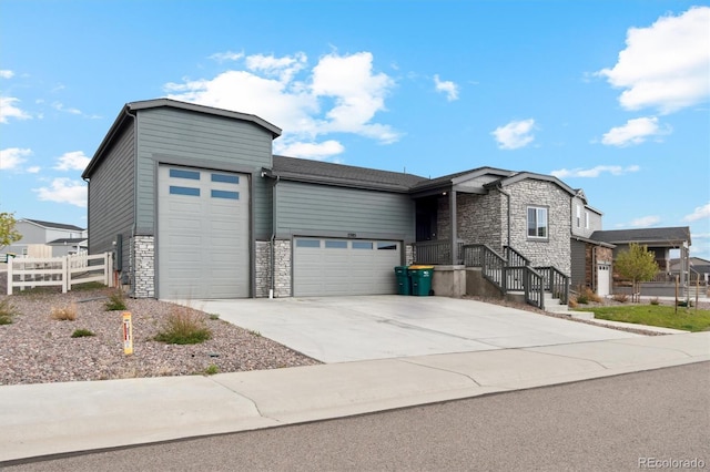view of front of home featuring concrete driveway, fence, stone siding, and a garage