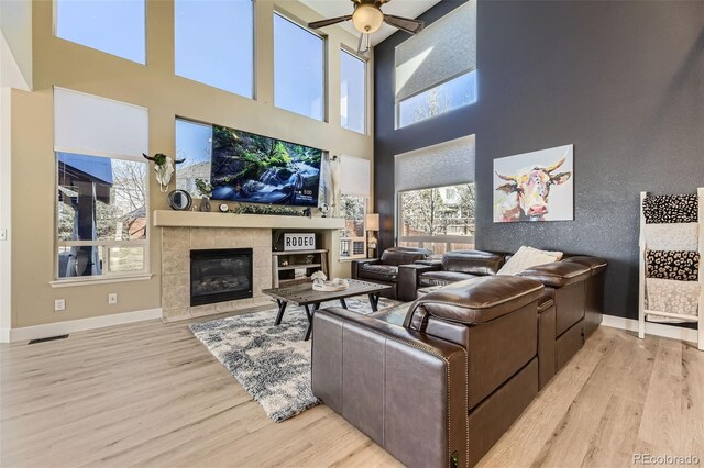 7378 Geode Ct, Castle Rock, CO 80108 - living area featuring ceiling fan, wood finished floors, a tiled fireplace, a high ceiling, and baseboards