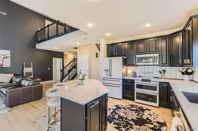 7378 Geode Ct, Castle Rock, CO 80108 - kitchen with stainless steel microwave, white refrigerator with ice dispenser, range with two ovens, open floor plan, and light wood-type flooring