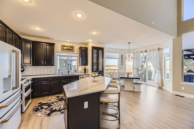 7378 Geode Ct, Castle Rock, CO 80108 - kitchen featuring white appliances, a sink, light wood-style flooring, a kitchen island, and decorative backsplash