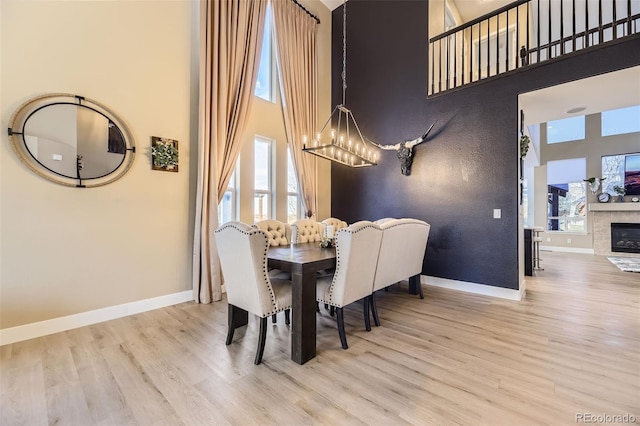 7378 Geode Ct, Castle Rock, CO 80108 - dining space with a high ceiling, wood finished floors, a chandelier, baseboards, and a glass covered fireplace