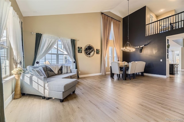7378 Geode Ct, Castle Rock, CO 80108 - living room featuring a chandelier, high vaulted ceiling, light wood-style flooring, and baseboards