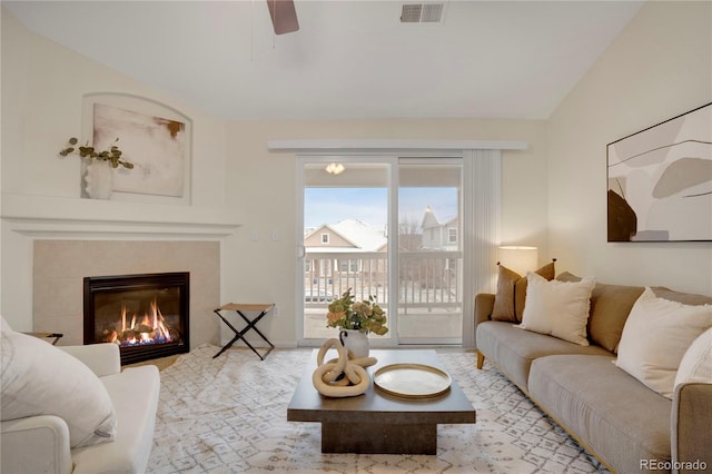 living room with lofted ceiling, a tile fireplace, and ceiling fan