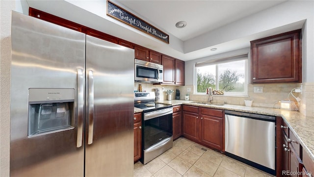 10759 Clermont St, Thornton, CO 80233 - kitchen featuring appliances with stainless steel finishes, tasteful backsplash, light stone counters, and light tile patterned floors