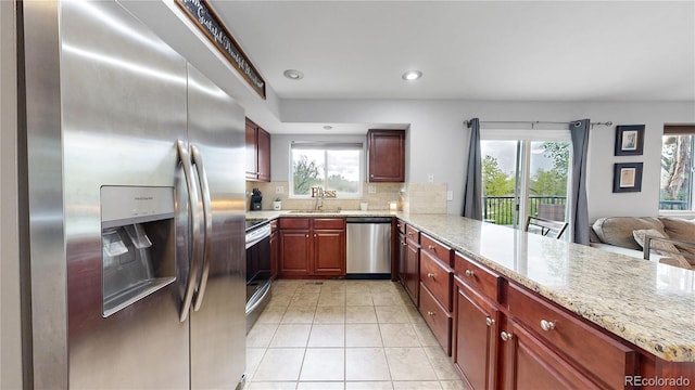 10759 Clermont St, Thornton, CO 80233 - kitchen featuring appliances with stainless steel finishes, a peninsula, plenty of natural light, light tile patterned flooring, and recessed lighting